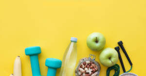 a pair of dumbbells and fruit on a yellow background